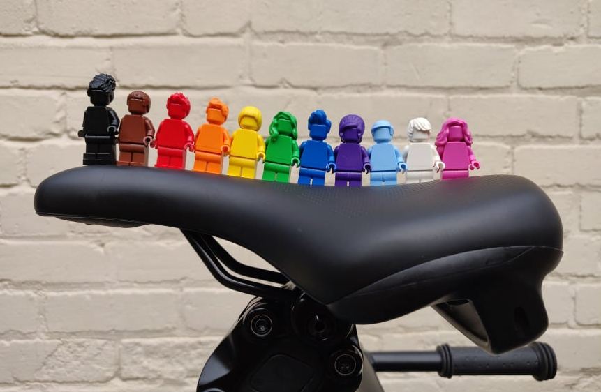 Rainbow lego minifigures lined up on a bike saddle