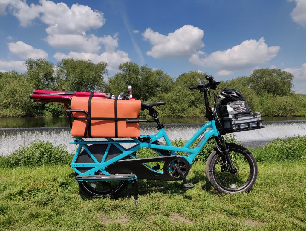 tern gsd cargo bike loaded with kits and tools in front of a weir on a sunny day
